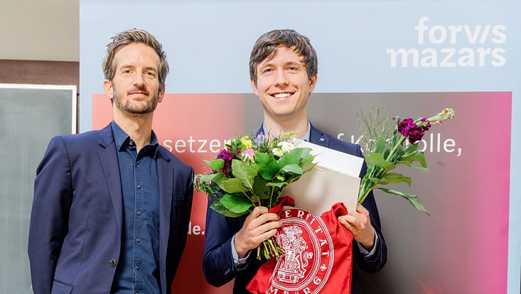 Masterstudierender mit Sponsor, zwei Männer nach Blumenübergabe