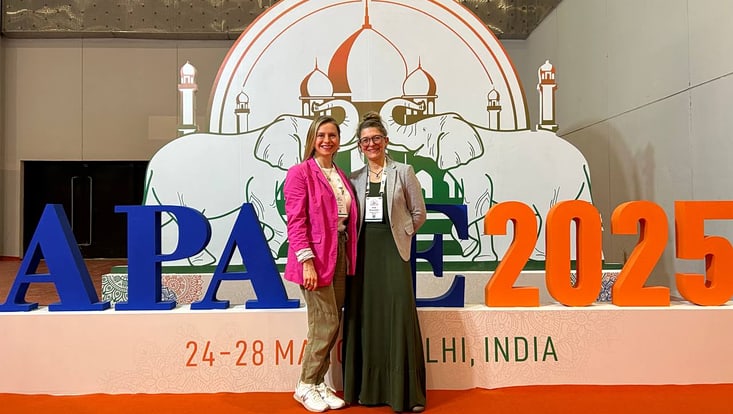 Zwei junge Frauen vor indischem Konferenz-Logo