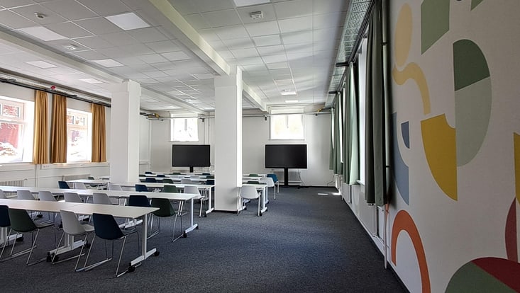 Blick in den neuen Seminarrraum AP1 112 von der Tür in Richtung Front, zu sehen sind die Sitzreihen und die zwei großen Bildschirme