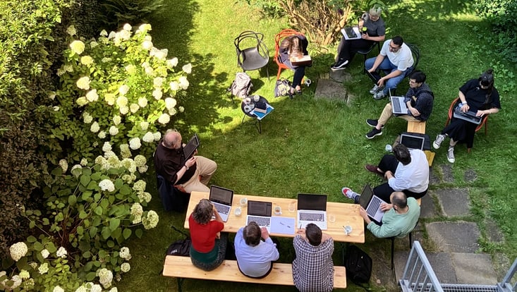 Summer School 2024. Ansicht aus der Vogelperspektive von Menschen, die draußen im Kreis sitzen und dabei arbeiten