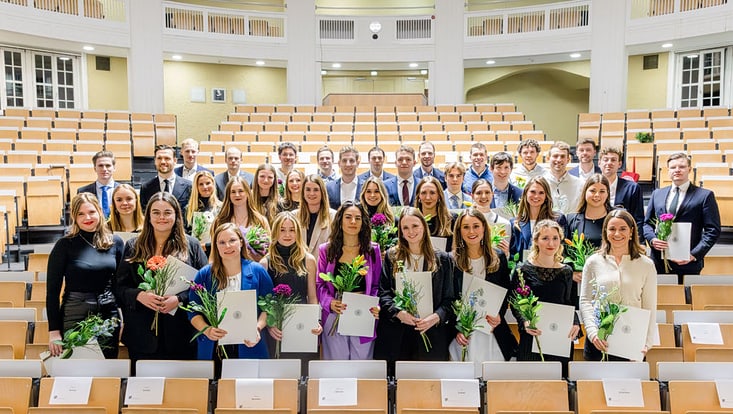 Gruppenfoto festlich angezogene junge Männer und Frauen im Hörsaal