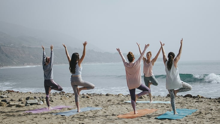 Menschen machen Yoga am Strand