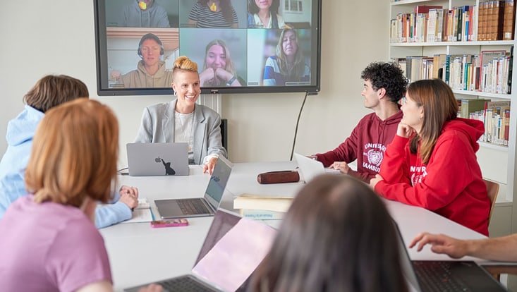 junge Menschen in Besprechung um Tisch und virtuell