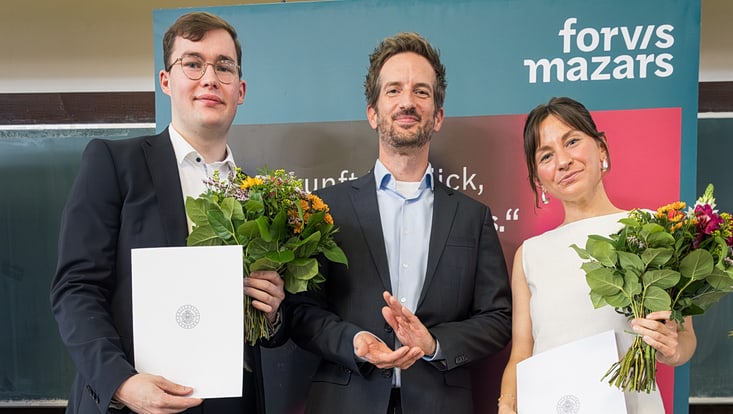 Zwei Männer und eine Frau vor Forvis Mazars Werbeaufsteller