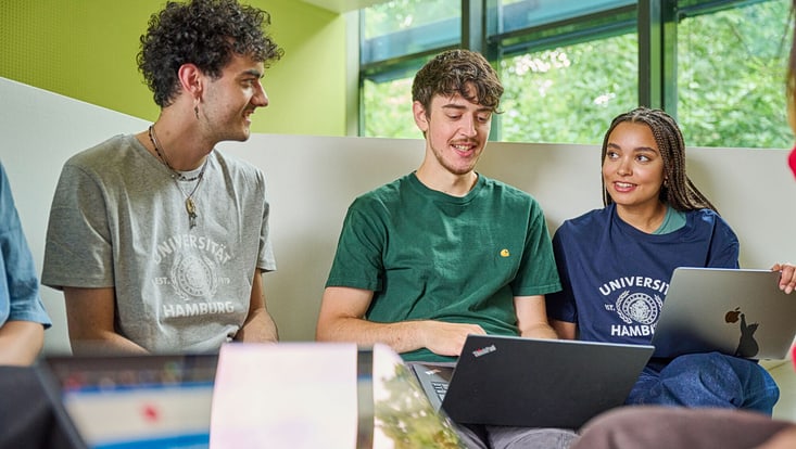 Zwei Männer und eine Frau sitzen an ihren Laptops