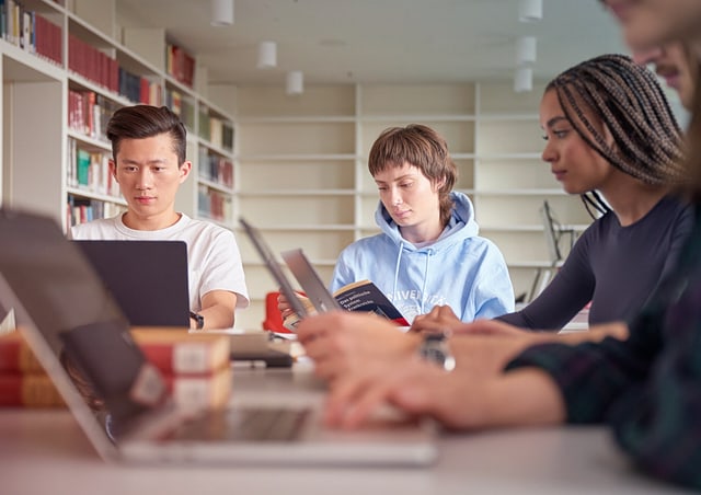 lehre-motiv-058-uhhs-640x452 Studierende sitzen um einen Tisch herum und arbeiten an einem Projekt.