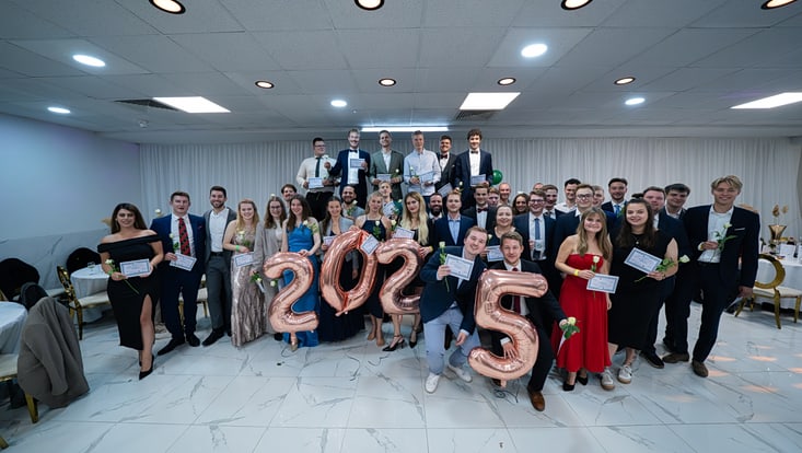 Gruppe junger Erwachsener in festlicher Kleidung mit Blume und Zeugnis in der Hand