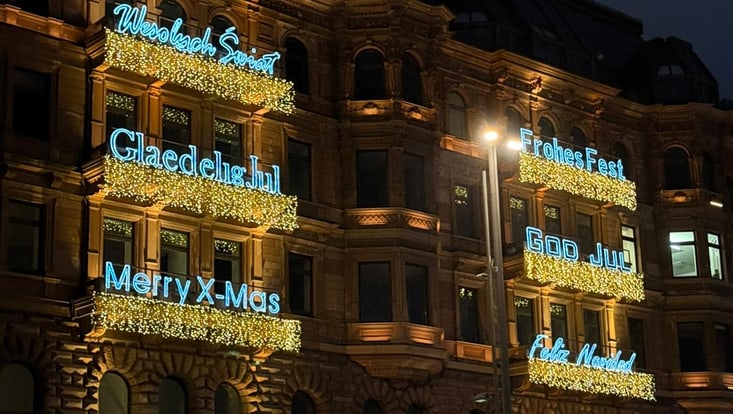 das alsterhaus mit leuchtenden glückwünschen zu weihnachten auf verschiedenen sprachen