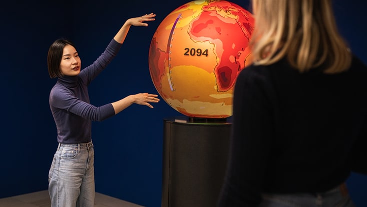 Eine Frau erklärt etwas anhand eines Globus.