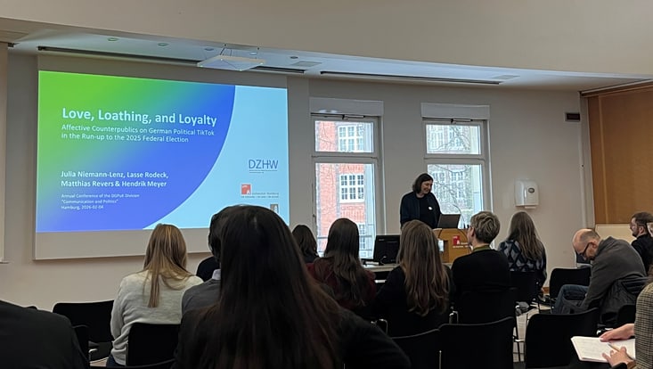 Bild von Vortrag auf der Tagung mit Titel des Vortrags auf der Leinwand