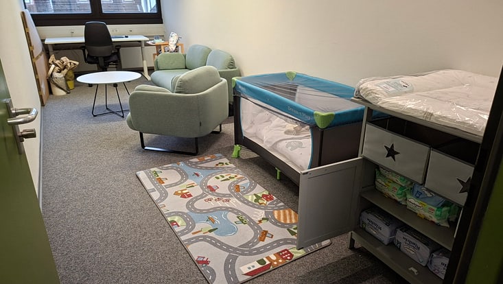 Ein Büro mit Babybett und Wickeltisch