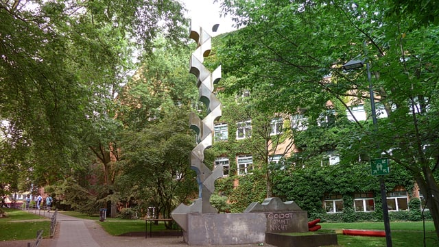 Seitlicher Blick auf AP1 mit Säule im Vordergrund Gebäude (AP1 an der UHH) iim Hintergrund mit einer silbernen Säule im Vordergrund - Dekorativ