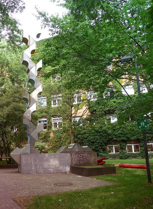 Seitlicher Blick auf AP1 mit Säule im Vordergrund Gebäude (AP1 an der UHH) iim Hintergrund mit einer silbernen Säule im Vordergrund - Dekorativ