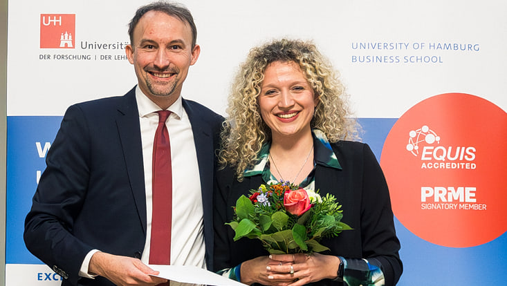Mann und Frau lachend mit Blumenstrauß und Urkunde