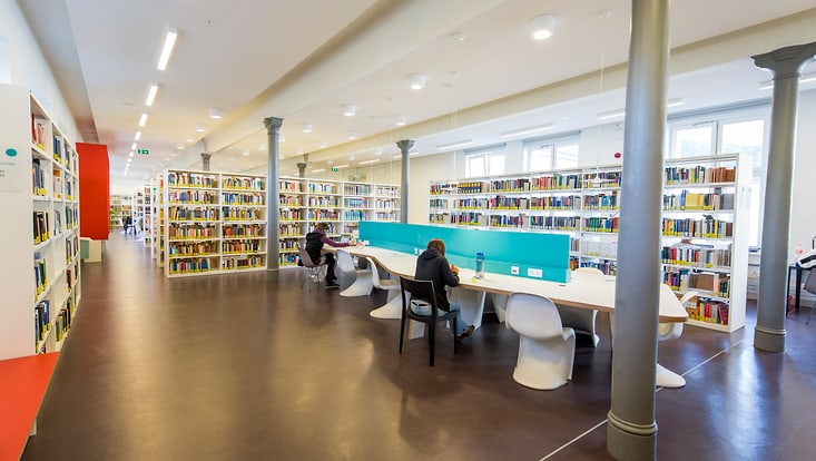 Person an liest an Tisch in Bibliothek