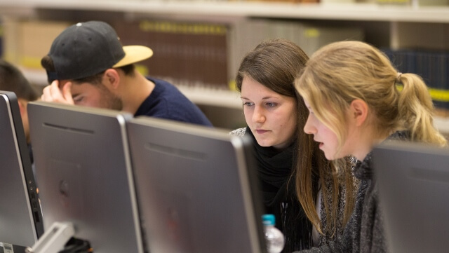 Drei Menschen arbeiten anComputern/Three people at desktop computers working