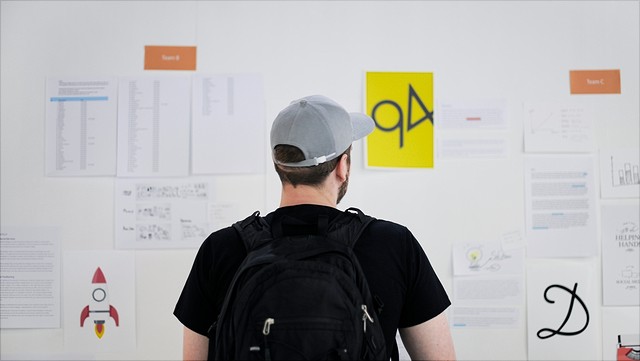 Praktikum/Internships ein Mensch mit Rucksack vor einer Pinnwand mit Zetteln/A person with a backpack in front of a bulletin board with lots of notes