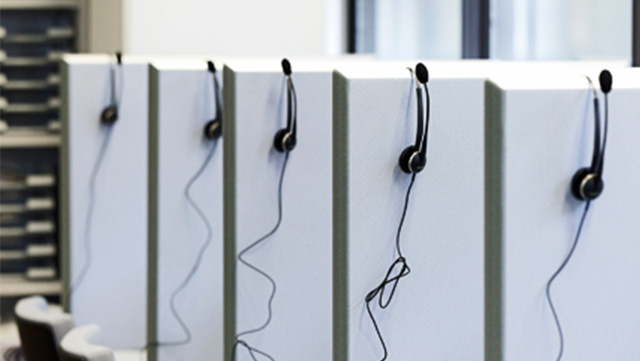 Hellgraue Trennwände im Telefonlabor, auf denen Kopfhörer für Umfragen sind