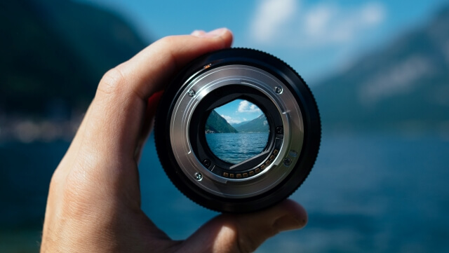 Suchen/Searching Kameralinse vor Wasserpanorama/Camera lens in front of a water scenery