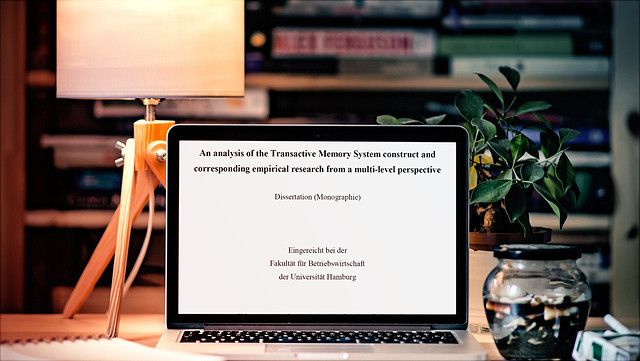 Schreiben/Writing offenes Laptop auf einem Schreibtisch mit Dissertation auf dem Bildschirm/Open laptop on a desk with a dissertation on the screen
