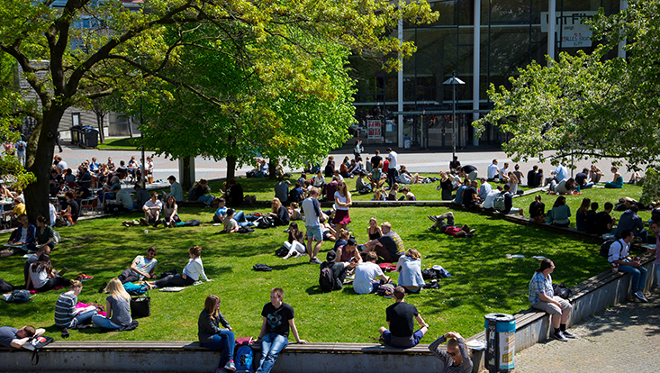 Studenten auf einer großen Wiese vor dem Audimax.