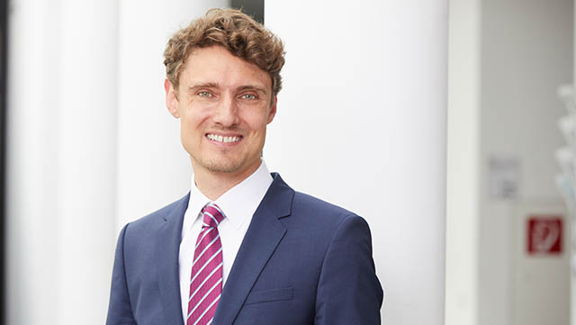 Hier steht Prof. Dr. Jonas Schreyögg in der Mitte vom Bild und lächelt in die Kamera.