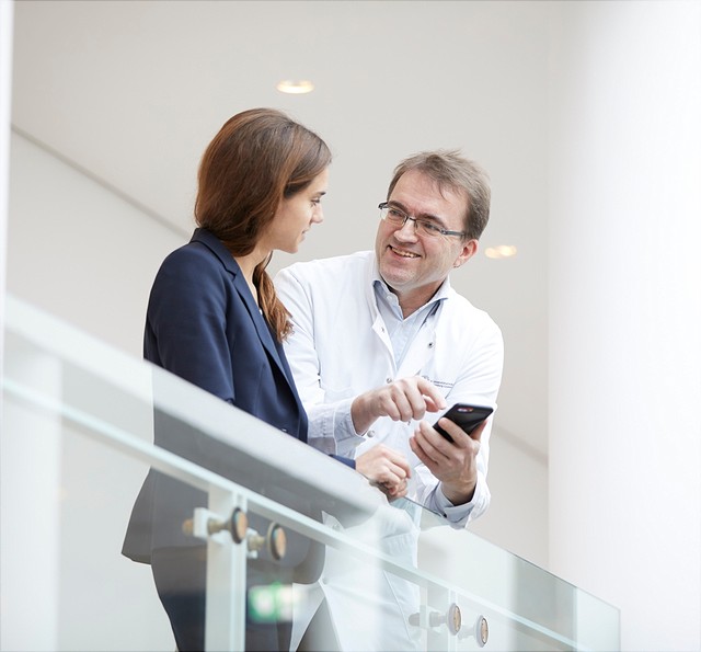 Auf diesem Bild unterhält sich Prof. Dr. Matthias Augustin mit Prof. Dr. Eva Oppel an einem Geländer im HCHE.