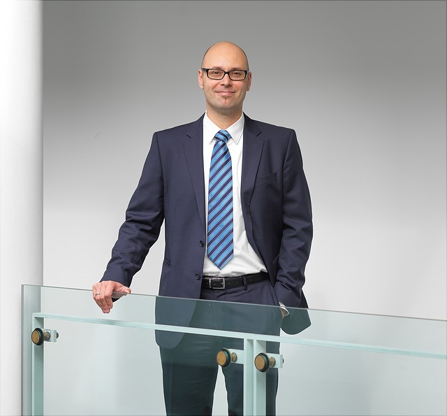 Prof. Dr. Tom Stargardt steht an einem Geländer im HCHE und lächelt in die Kamera.