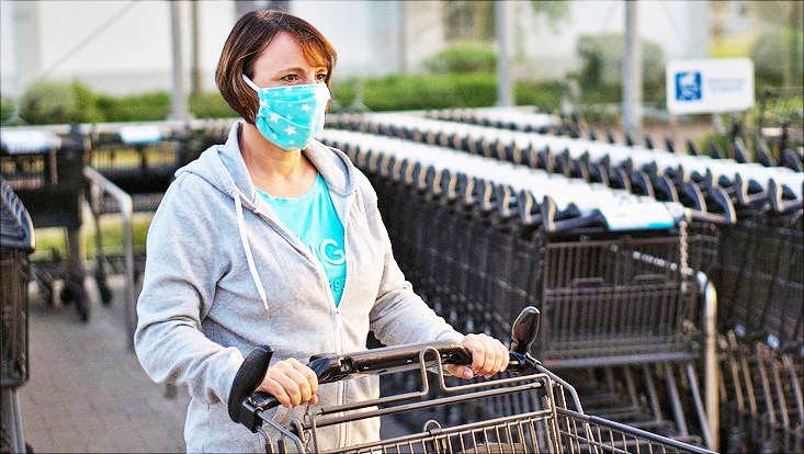 Frau mit Einkaufswagen und Mund-Nasen-Schutz