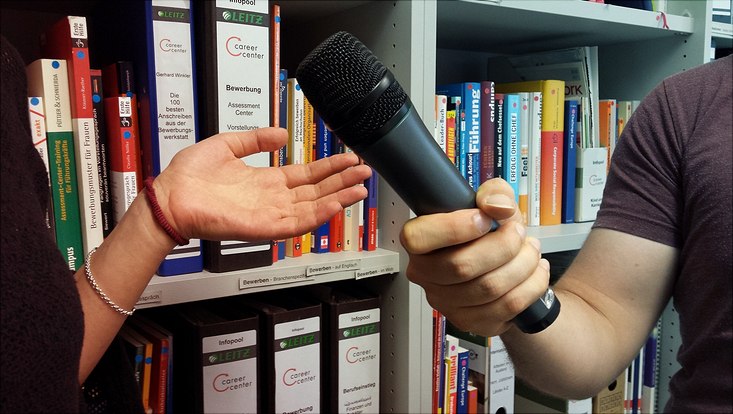 Interviewsituation: Hand des Interviewers mit Mikrofon und gestikulierende Hand der Interviewten