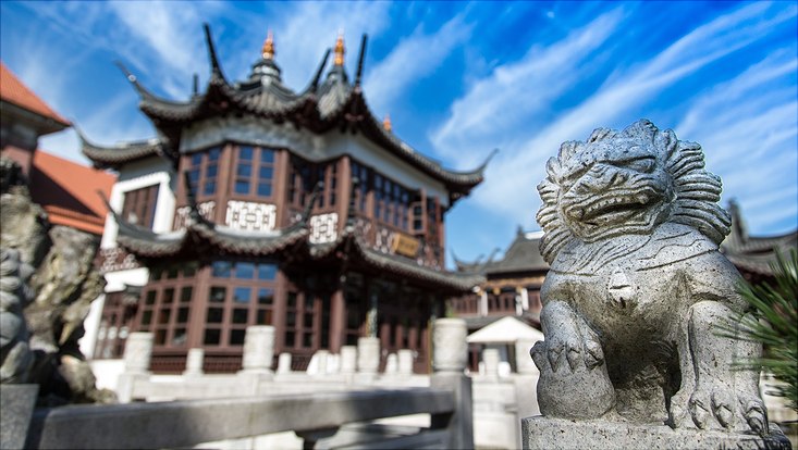 733x414-schaller stone lion guarding a two-story chinese tea house with bright sky in the background