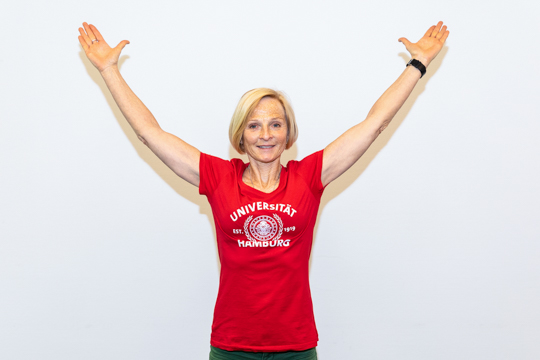 Chest stretch Variant 2: Stretching exercise: Chest stretch: A person holds both arms stretched up.