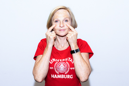 Smoothing out (step 2) Eye relaxation exercise Smoothing out: A person has their hands placed on their face. Their index fingertips touch their cheek.