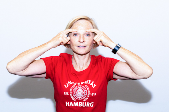 Smoothing out (step 2) Eye relaxation exercise Smoothing out: A person has their hands at the side of their face next to their eyes. Their thumbs are just in front of their ears, and their index fingers are touching their temples.