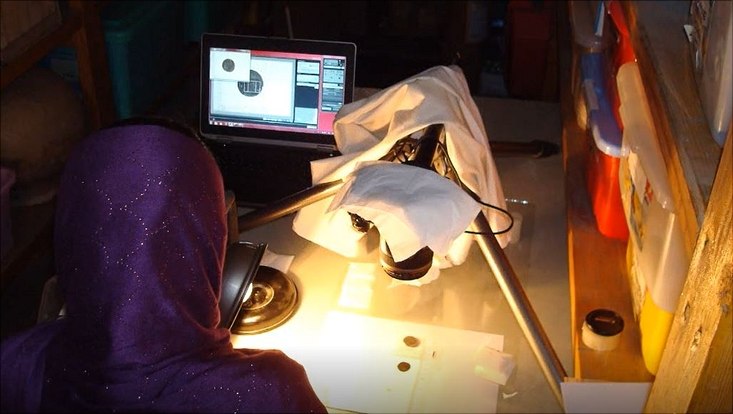 Junge Afghanin arbeitet an Münzfunden, von ihr ist nur der Rücken zu sehen