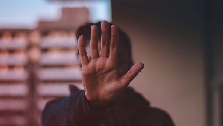 Person, die die Hand hebt, um die Aufforderung "Stop" zu symbolisieren