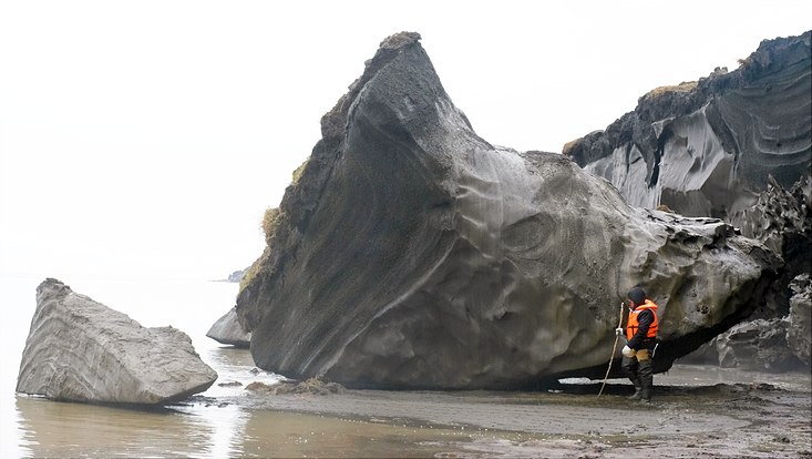 Ein großer Brocken Landmasse ist an einer arktischen Küste abgebrochen