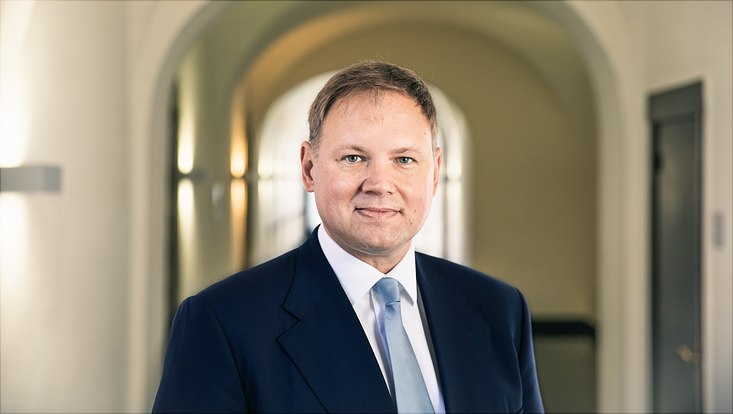 Portrait of President Hauke Heekeren beneath the archway.