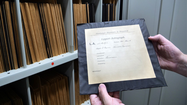 A view of the cupboard holding the photographic plates at the Hamburg Observatory— in the foreground a photographic plate from 1913.