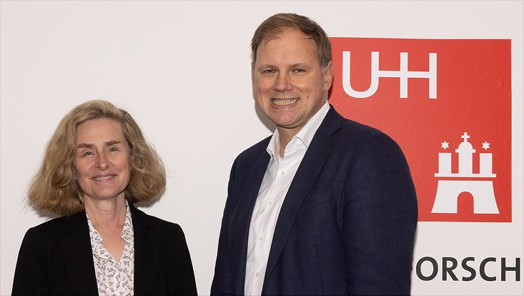 Die neue Präsidentin der Indiana University, Pamela Whitten, und Universitätspäsident Hauke Heekren stehen vor einer weißen Wand mit rotem UHH-Logo
