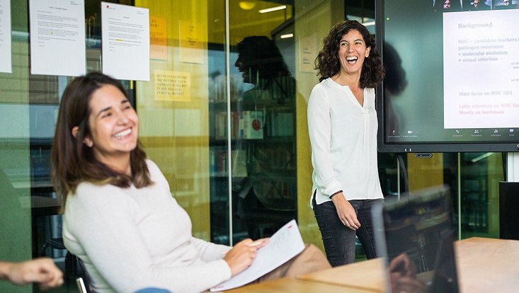 Zwei lachende Frauen in einem Konferenz-Raum