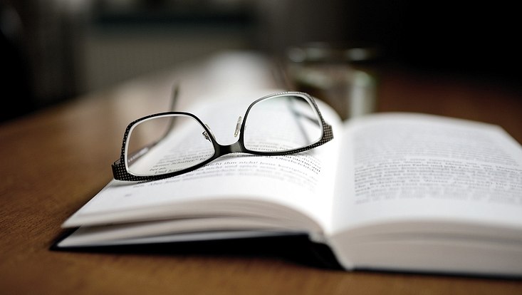 Symbolbild - aufgeschlagenes Buch und Brille