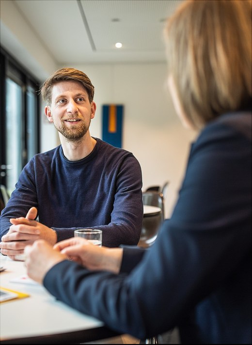 Zwei Personen sitzen am Tisch und unterhalten sich freundlich