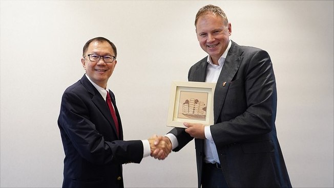 Professor Ho Teck Hua (l.) überreicht Prof. Dr. Hauke Heekeren einen Kunstdruck mit einer architektonischen Anmutung des NTU-Campus