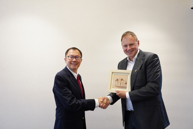 Prof. Ho Teck Hua (l.) überreicht Prof. Dr. Hauke Heekeren einen Kunstdruck mit einer architektonischen Anmutung des NTU-Campus