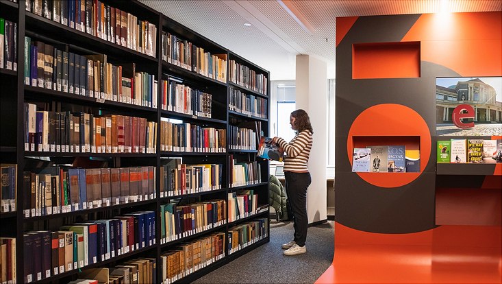 Frau vor Bücherwand in einer Bibliothek