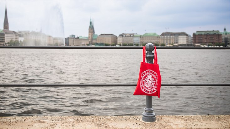 Ein Stoffbeutel mit den Logo der Uni Hamburg hängt an einem Geländer an der Binnenalster