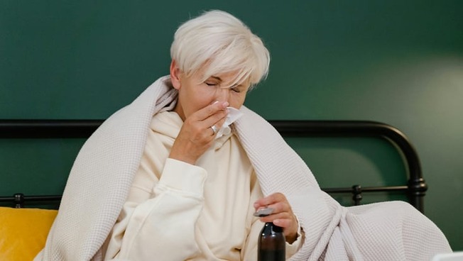 A woman lying in bed with cold symptoms