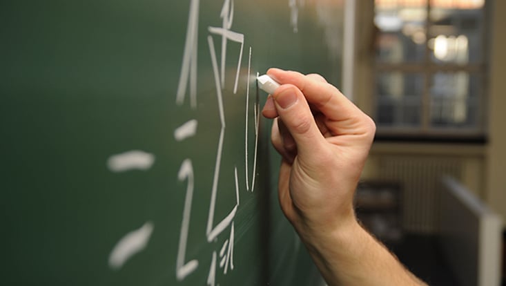 Student schreibt Zahlen an eine Tafel