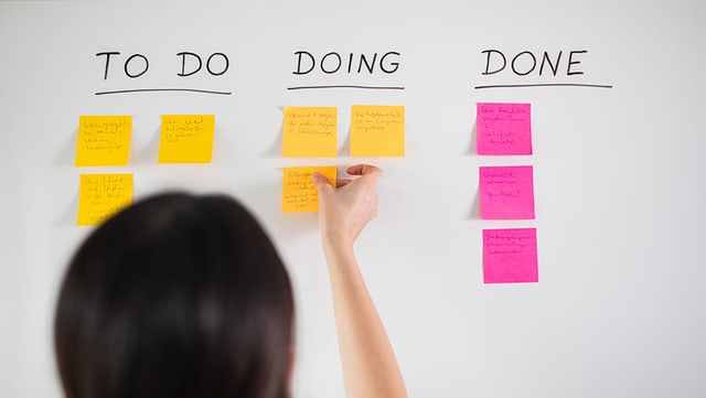 Kontakt und Hilfe Eine Mitarbeiterin arbeitet an einem Kanban-Board, das eine to-do-Liste abbildet